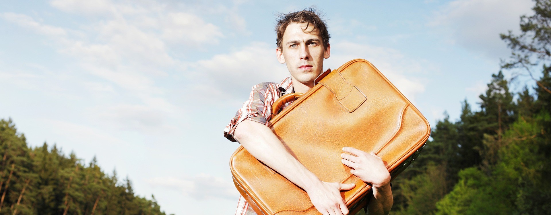 Desperate looking man holding a piece of luggage