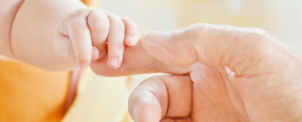 Babies hand holding on to adult finger