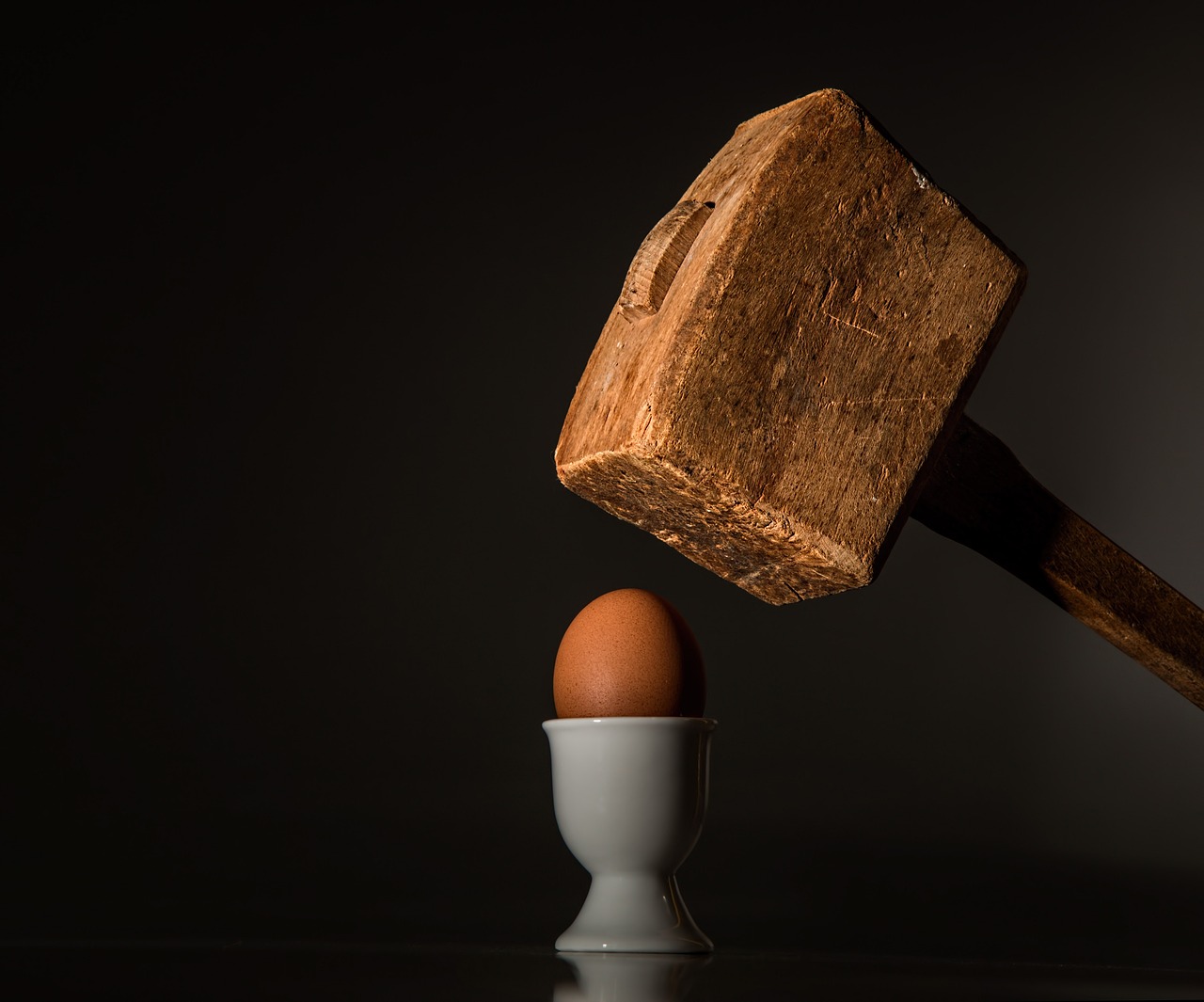 Wooden mallet about to crush a poached egg