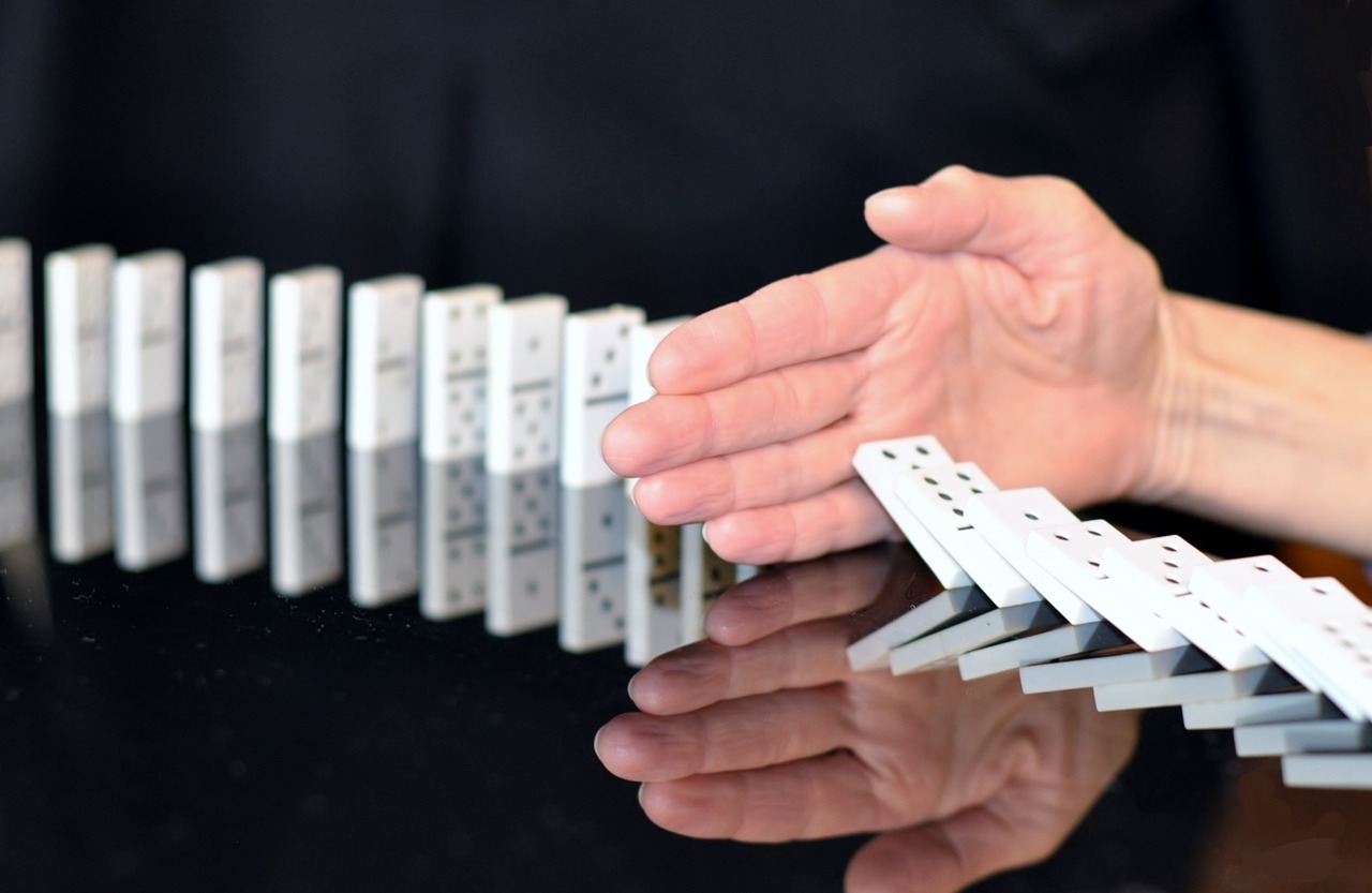 A break in the action as a hand stops the dominos collapse