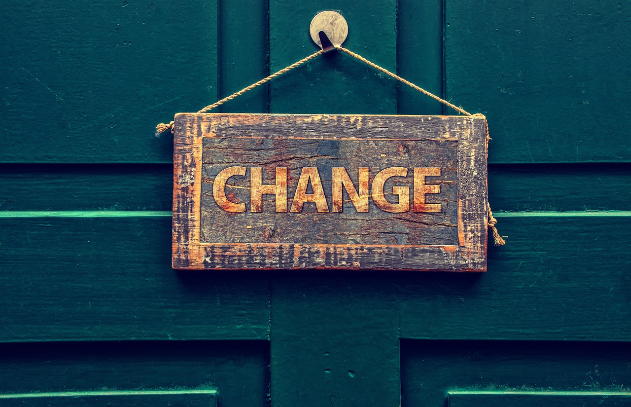 Old wooden sign saying "Change" hung on a green door