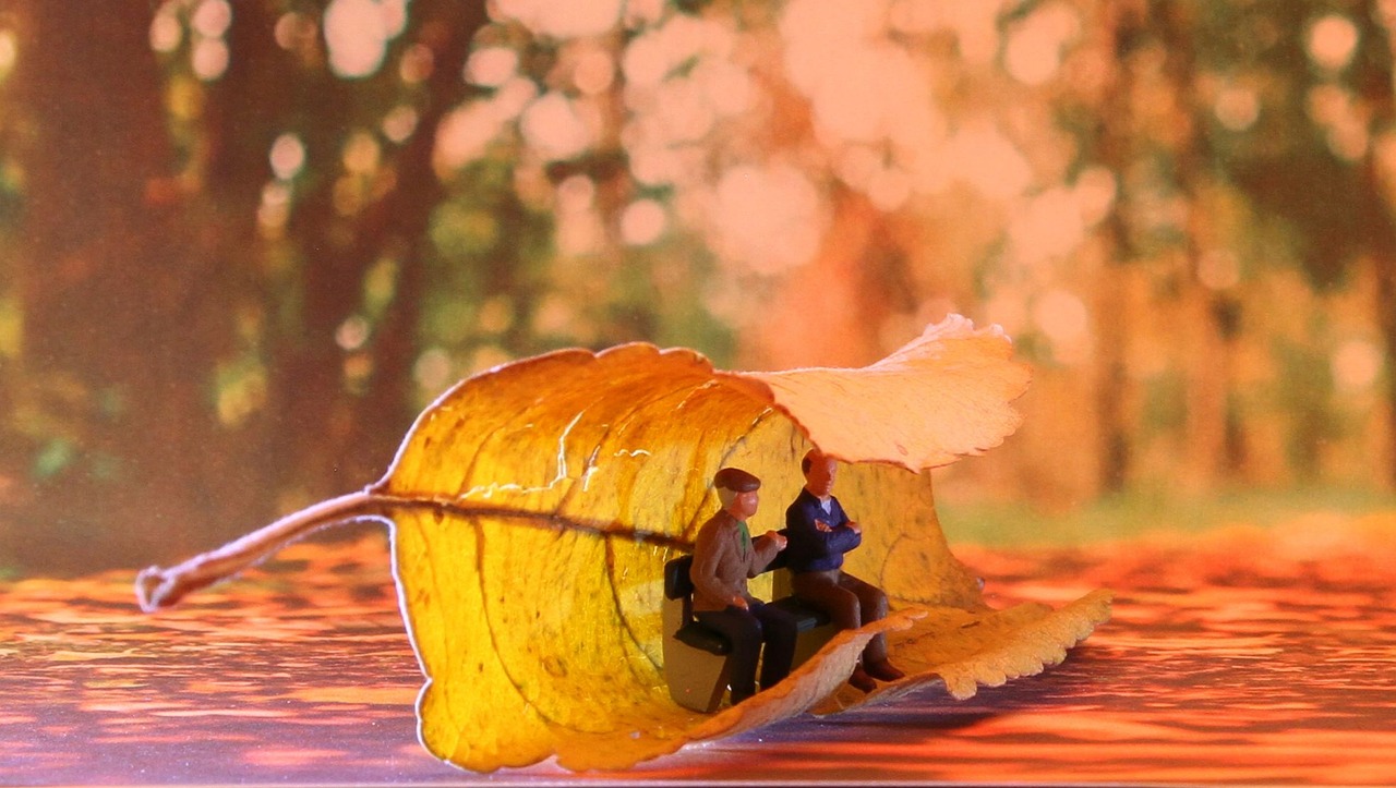 Plastic characters on a park bench curled by a huge leaf